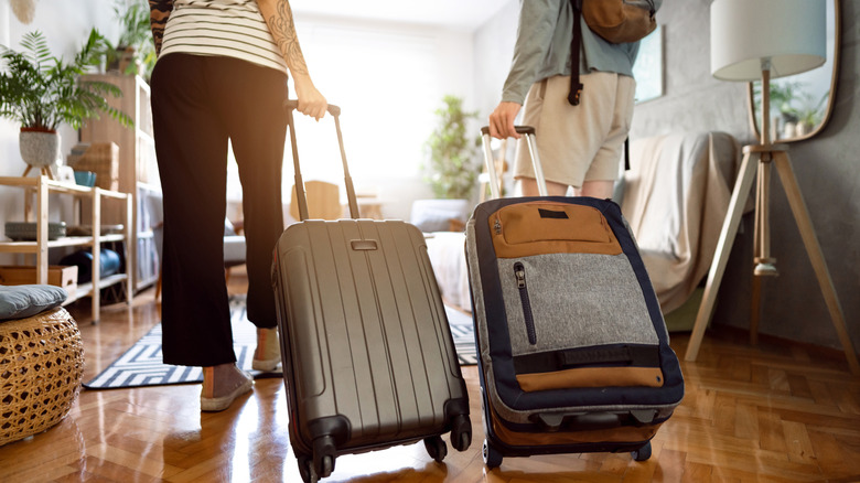 Two people holding their suitcases and walking into an accommodation