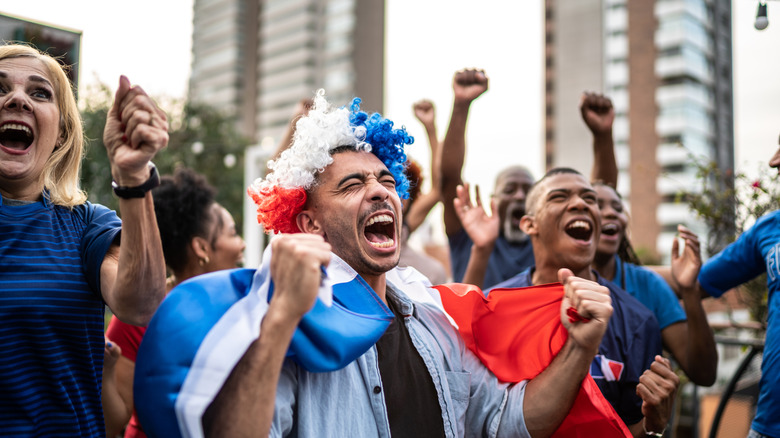 Cheering football fans in the streets wearing colorful wigs and holding flags