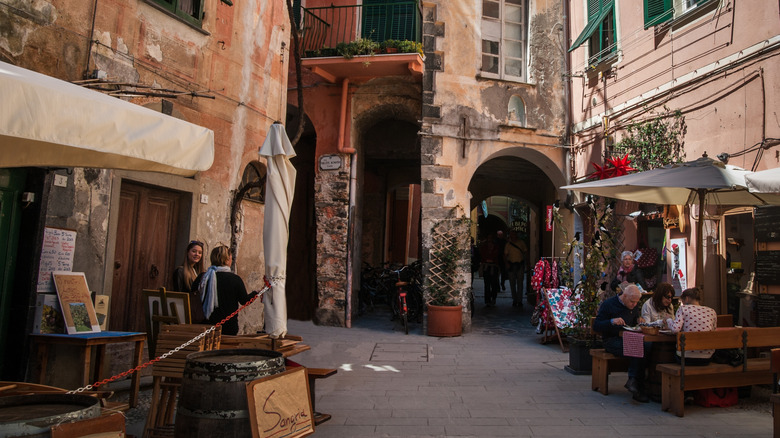 People dining on a narrow street in Italy