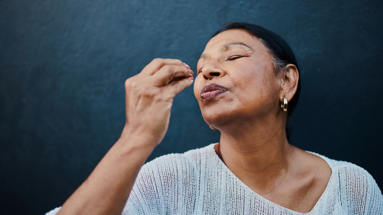 A woman does a "chef's kiss" gesture by tenting her fingers while kissing their tips