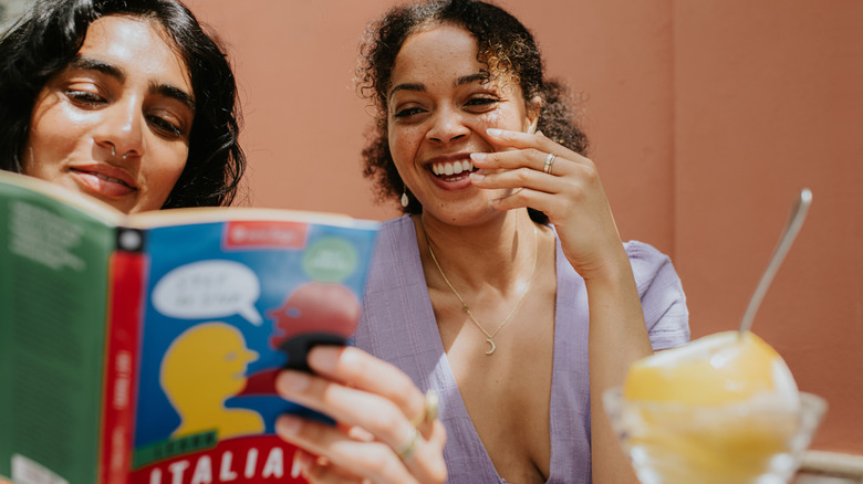 Two women studying Italian from a book