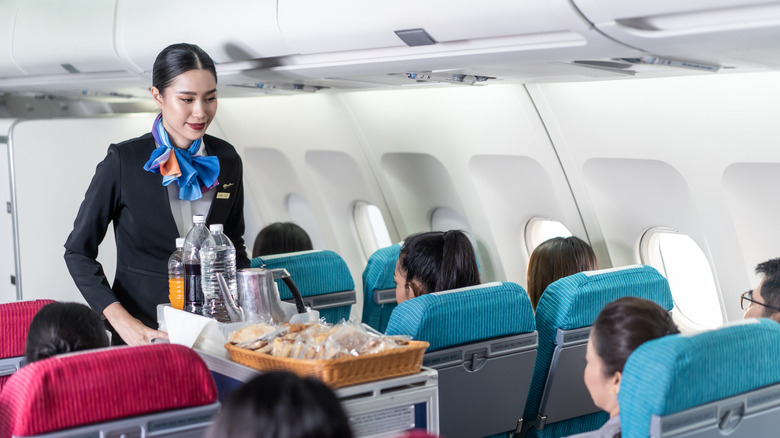 Flight attendant coming down the aisle with the drink tray