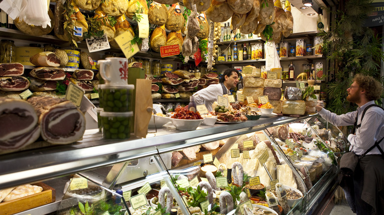 Man talking with a meat and cheese vendor at Mercato Centrale in Florence, Italy