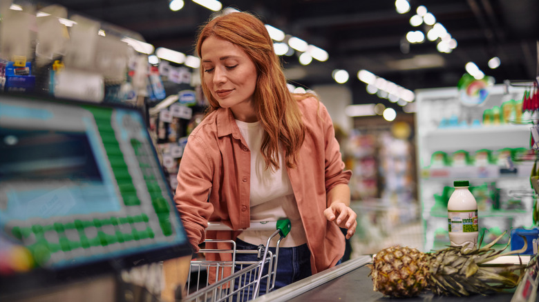 A woman unloading her groceries on a supermarket conveyor belt