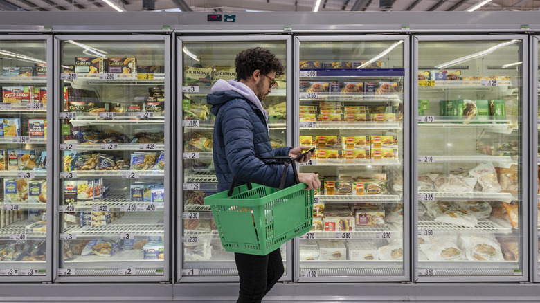 Young man in a grocery shop holding a basket