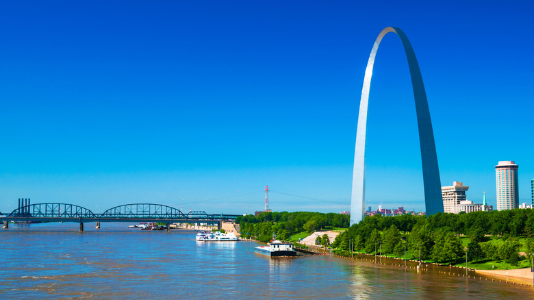 The Gateway Arch and boats on the Mississippi River, with a bridge across the river visible ahead