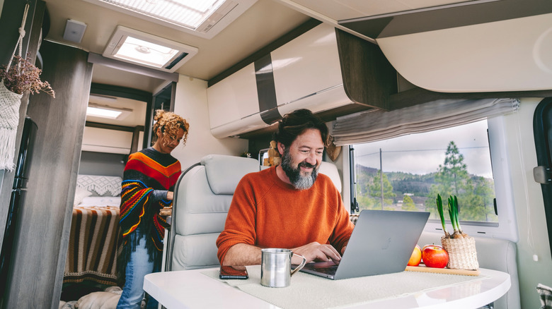 Man using laptop inside camper van