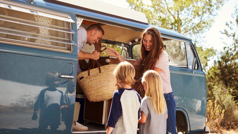 A happy family takes a bag out of their camper van