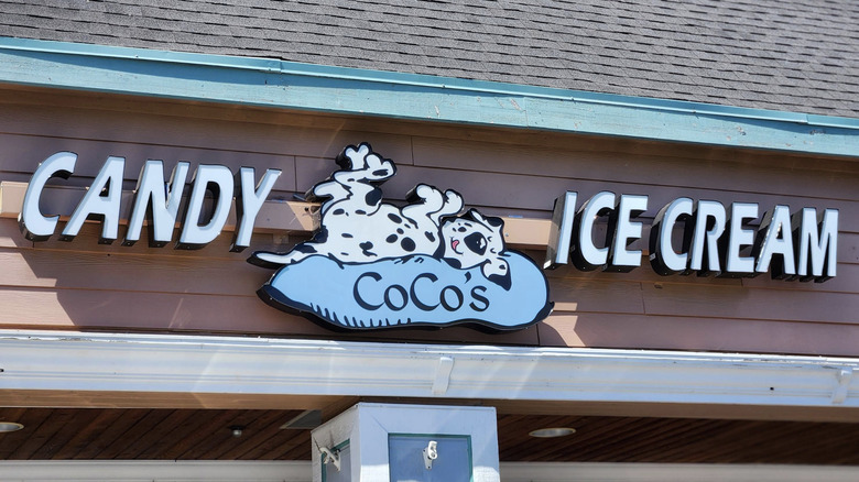 A storefront sign that says "candy" and "ice cream" on either side of the Coco's logo, which features a spotted dog on a blue pillow.