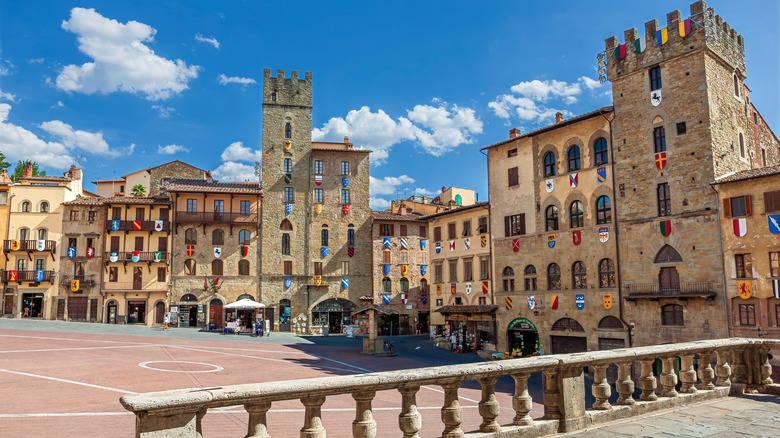 Stone buildings and a stone tower in Arezzo's Piazza Grande, Italy.