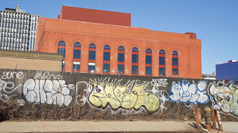 A graffiti covered fence in front of an old warehouse in Gowanus, Brooklyn
