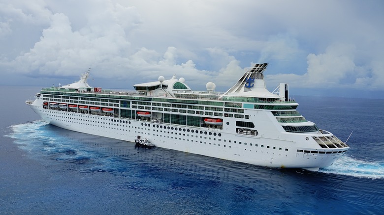 White cruise ship sailing in ocean with small craft parked alongside