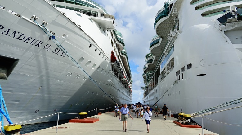 Two cruise ships docked side by side as passengers disembark between them
