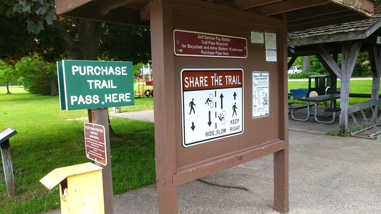 Signage at a Glacial Drumlin Trail trailhead with usage and trail pass payment information