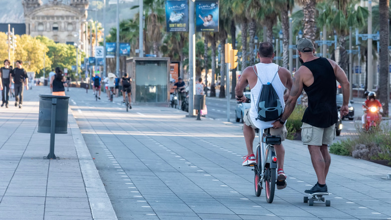 Men cycling and skateboarding fown a street in Barcelona, Spain
