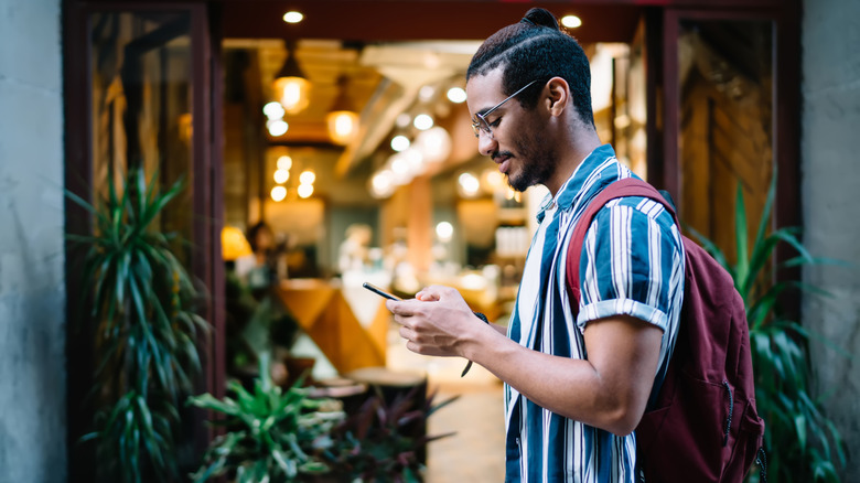 A tourist with a backpack, looking at his phone