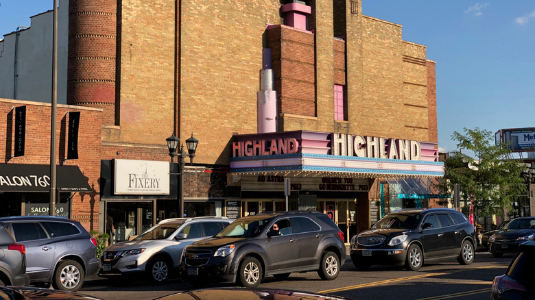 Cars on a road in front of a theater and stores