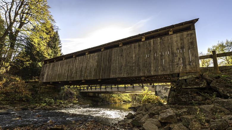 A historic covered bridge above a ravine in Salem, Ohio, on a sunny day with clear skies.