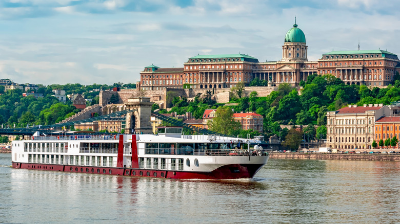 River cruise ship on Danube river with Royal Palace at background, Budapest, Hungary