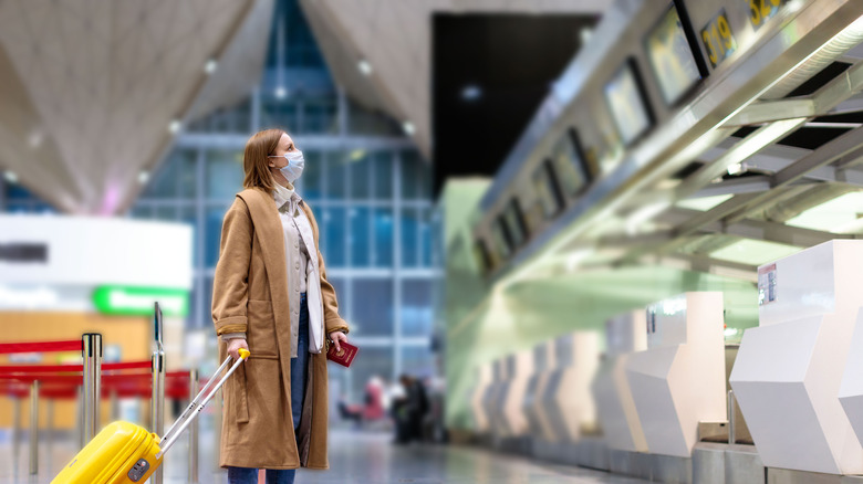 woman airport checking flight cancelations