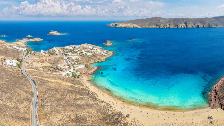 Aerial view of Agios Sostis Beach with its yellow sand, blue water and lack of people, with rocky islands off the coastline