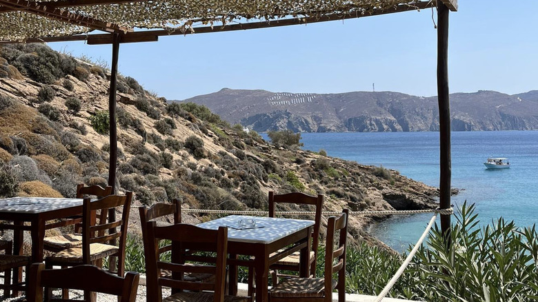 The patio at Kiki's Tavern with tables and chairs and a view of a boat on the water