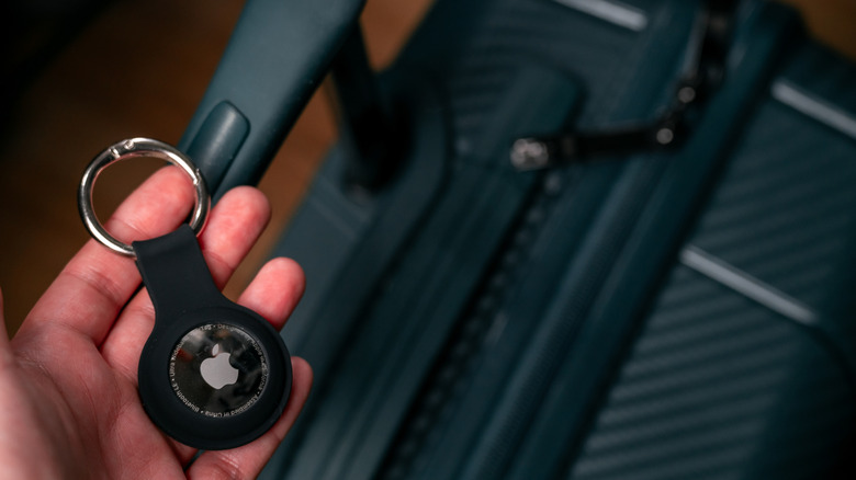 Person putting Apple AirTag in suitcase