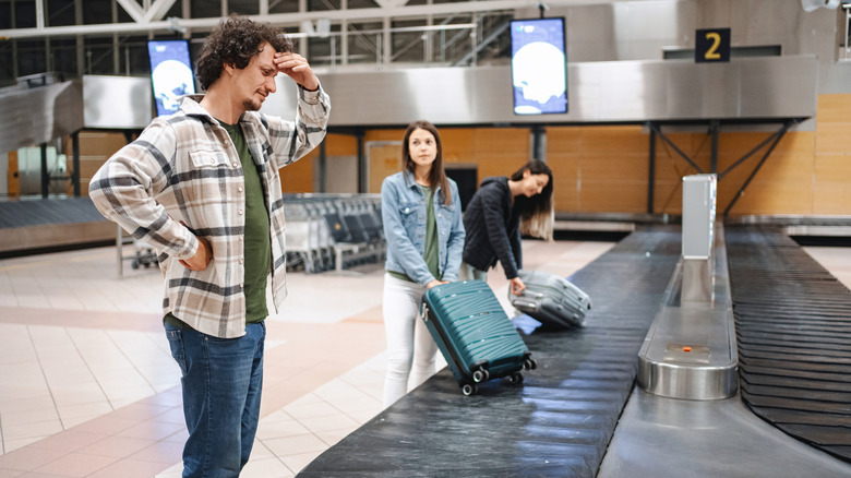 Man looking confused while standing near an airport luggage carousel