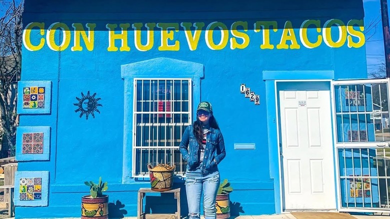 A woman stands in front of Con Huevos Tacos in San Antonio, Texas