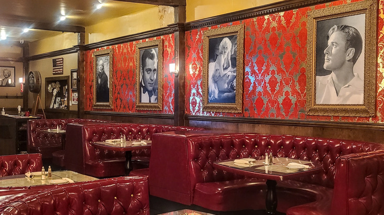 Black and white portraits of film stars hang on a wall above shiny, red banquettes in Café La Maze in National City