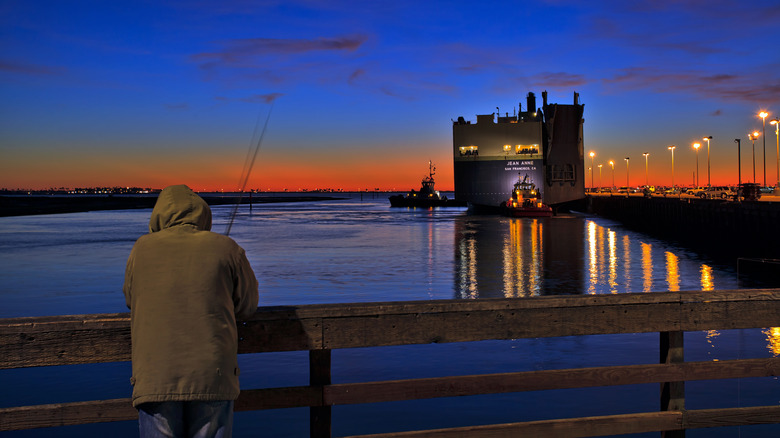 A man fishing from a pier at sunset in National City, California