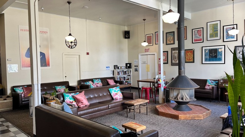 Framed art and leather sofas around a stove in the common room at HI San Francisco Fisherman's Wharf Hostel.