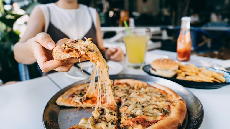 Woman taking a slice from a pizza