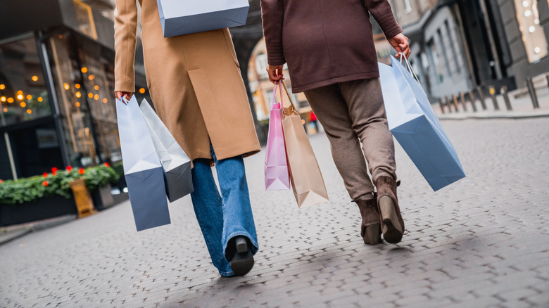 Two women walking down a street carryiny shopping bags