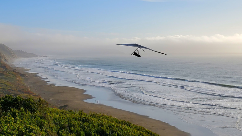 Hang glider flying above beach and ocean at Fort Funston, San Francisco