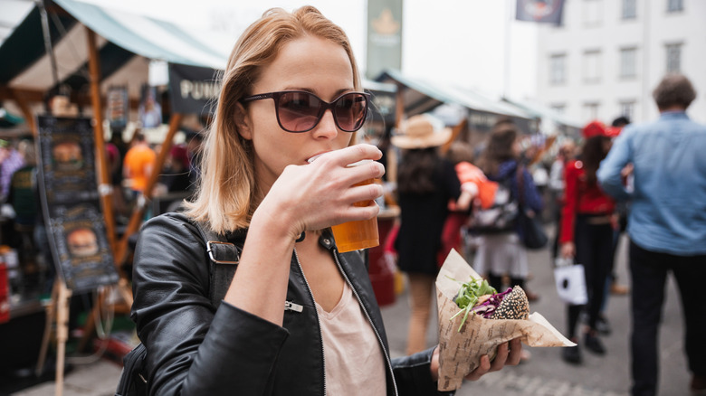 Woman holding a beer and burger at a food festival