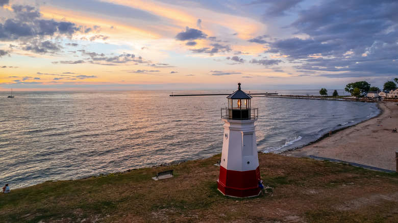 A lighthouse next to a beach at sunset in Ohio.