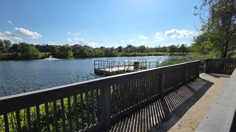 The Preserve at McCormick Park in Euless, Texas, with a wooden boardwalk overlooking a peaceful pond, dock, fountain, and surrounding greenery