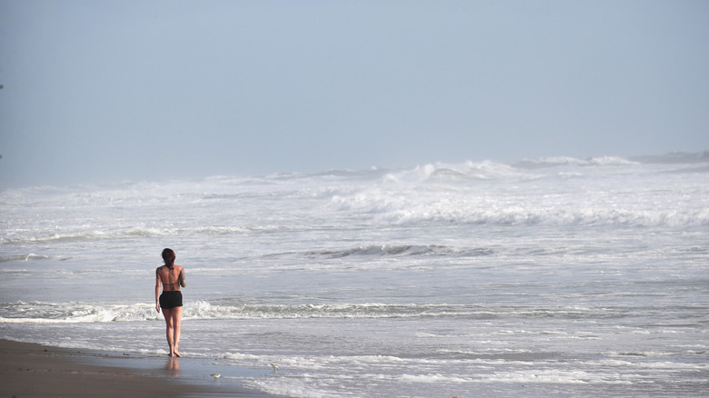 Woman standing at edge of rough waters