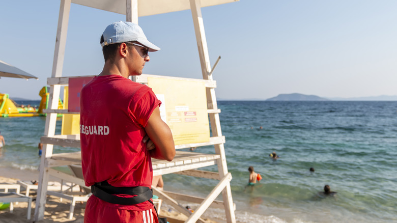 Lifegaurd standing on beach watching swimmers