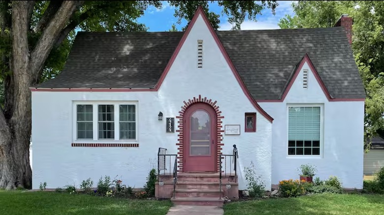 front of white cottage with red trim and small steps