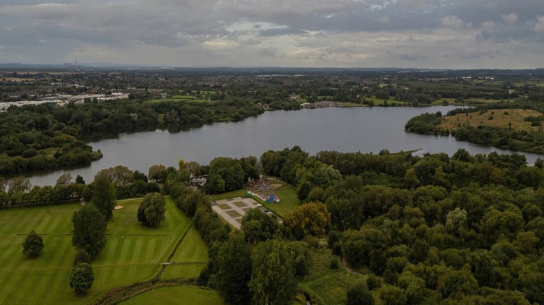 Wide aerial view of Pennington Flash Nature Reserve with its lake and surrounding trees, fields, and walking trails.