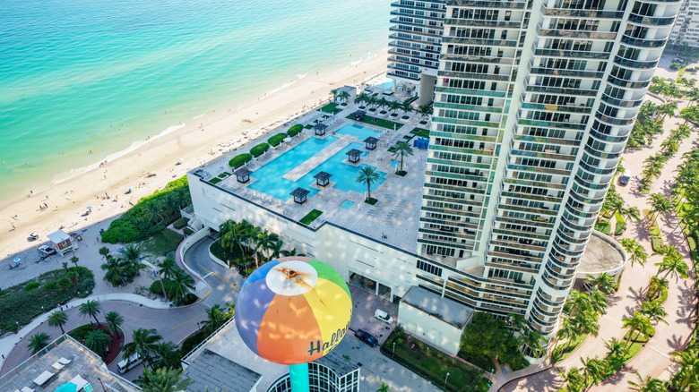 Aerial view of hotel, pool, and shoreline in Hallandale Beach.