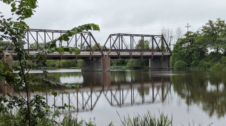A rusty steel truss bridge crossing the Châteauguay River at Domaine-de-la-Pêche-au-Saumon in Sainte-Martine, Quebec