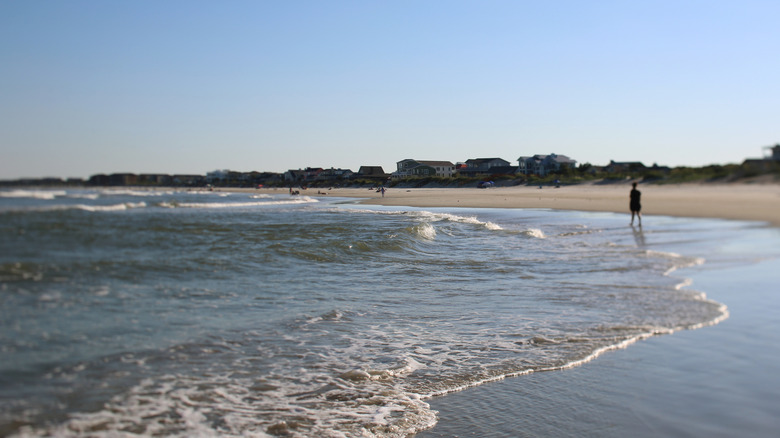 A scenic view of the beach and wave on Pawleys Island with a man on the horizon