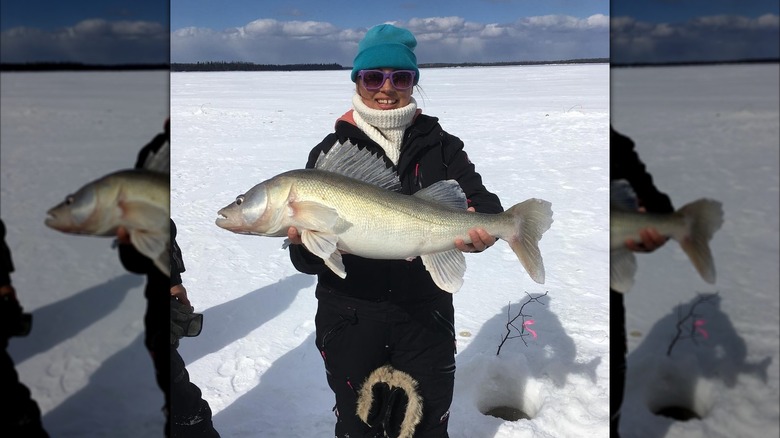 A woman holds a massive walleye on the frozen surface of Lake Abitibi in Canada