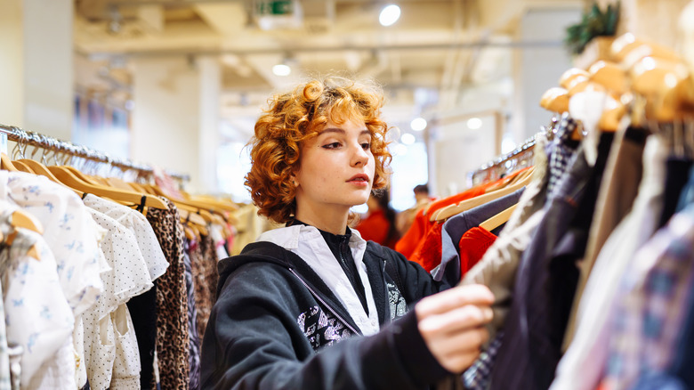 woman looking through a rack of clothes, shopping