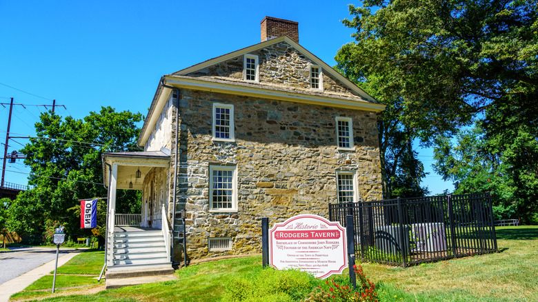 The stone exterior of the Rodgers Tavern in Perryville, Maryland, surrounded by trees