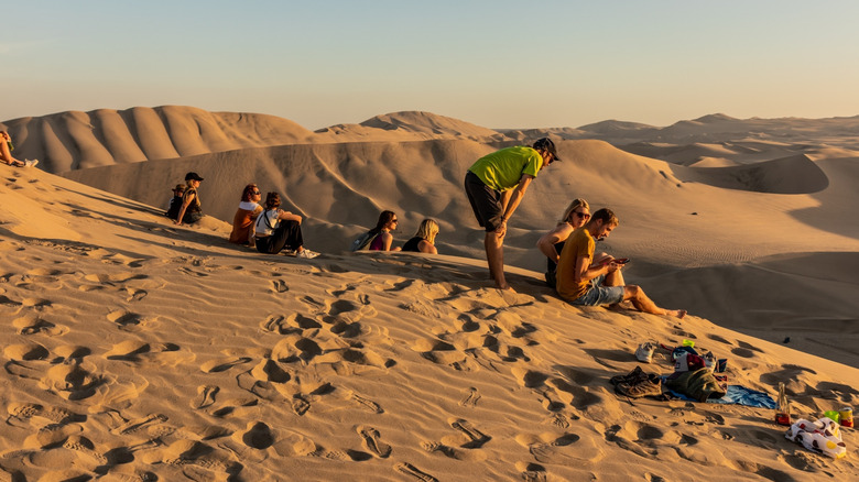 People sitting on the sand dunes near Ica, Peru