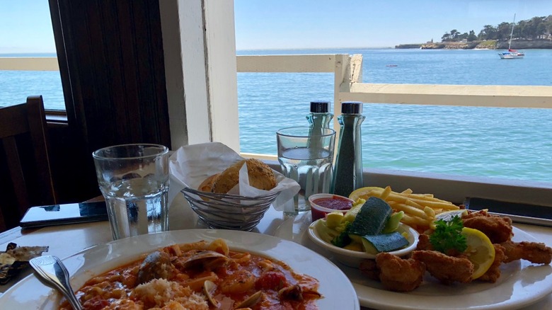 A plate of fish and chip and a seafood stew on a table overlooking the ocean in Santa Cruz, California.